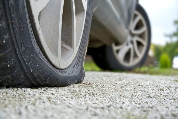 Close-up of Flat rear tire on car. Damaged rear wheels on parking place. The right rear broken weel.